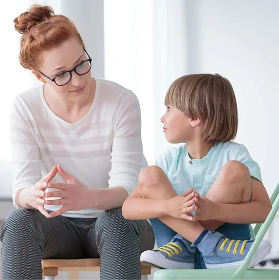 A woman and child sitting on the floor talking.